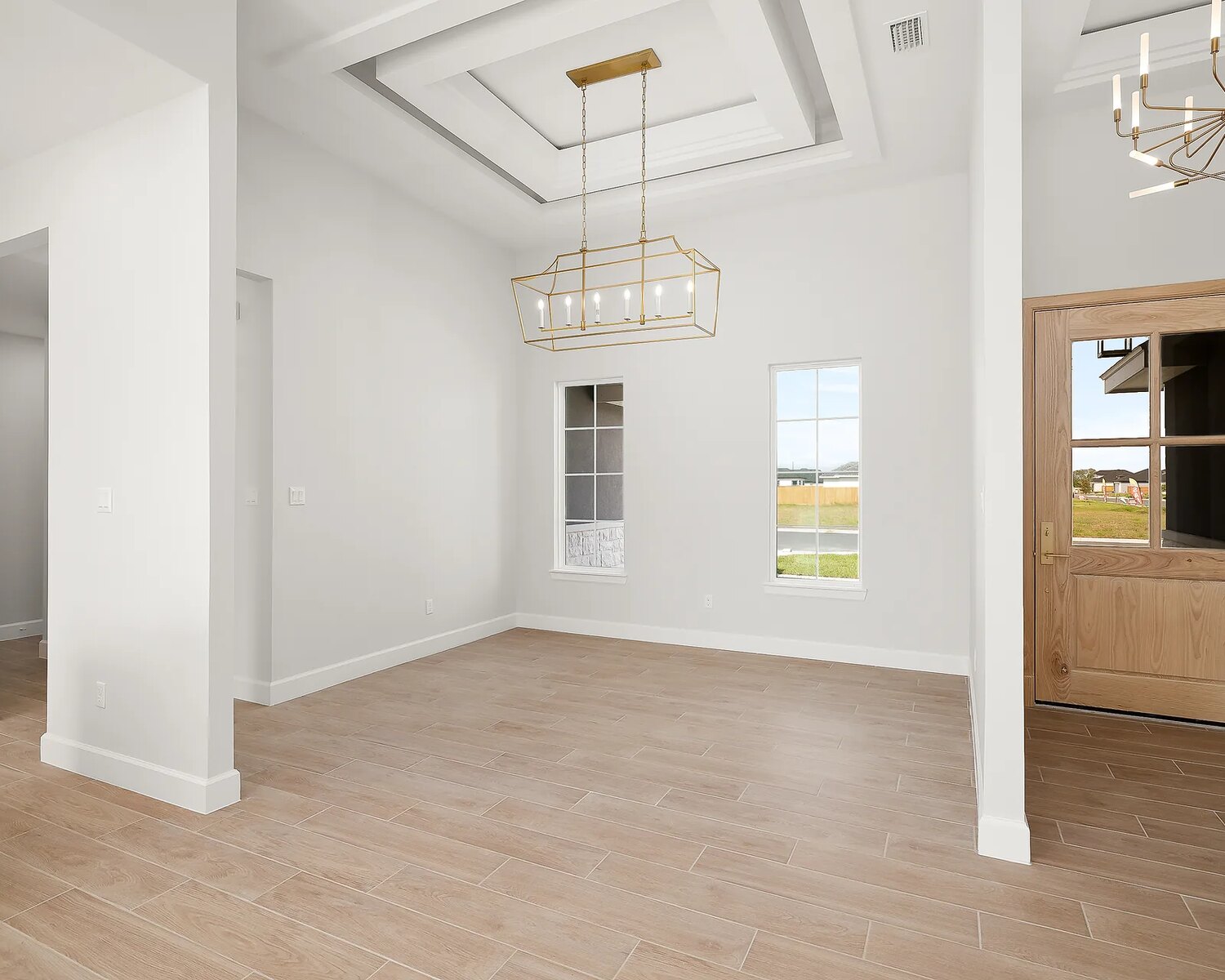 Dining area with coffered beam ceiling, linear lantern chandelier, and warm wood door